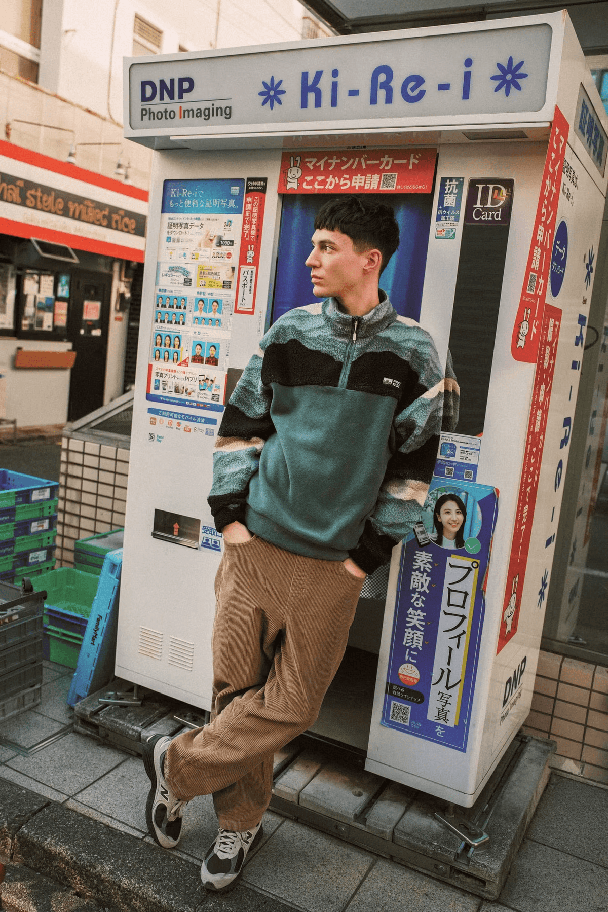 Homme en polaire verte à demi-zip et pantalon beige posant en ville